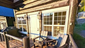 Une terrasse en bois avec des fauteuils Adirondack et un barbecue.
