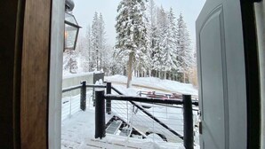 Un espace extérieur enneigé avec un escalier menant à une terrasse, le tout entouré d’arbres couverts de neige.