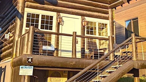 Une cabane en rondins dotée d’un balcon, de grandes fenêtres et d’un escalier.