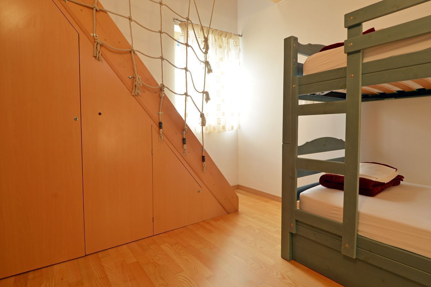 Un llit superposat amb escala de fusta i un petit armari amb porta corredissa.