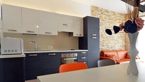 A modern kitchen with dark cabinets, a white countertop, and a stone backsplash. - Beautiful villa 400 meters to beach with 2 pools (Banjole)