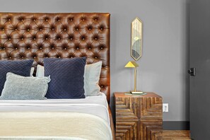 A bedroom with a tufted headboard, a bedside table with a lamp, and a mirror on the wall. - Luxury WeHo Home w/ DT Rooftop Views + Nightlife (Nashville)