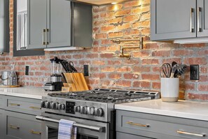 Een keuken met een bakstenen muur, roestvrijstalen apparatuur en moderne kastjes.