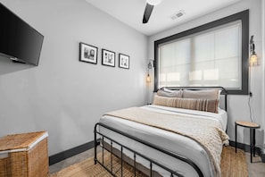 Una camera da letto con un letto, una TV montata a parete e tre quadri appesi.