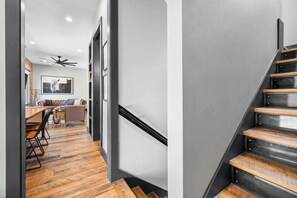 Een modern interieur met een trap, houten vloeren en een zithoek met een bank en stoelen.