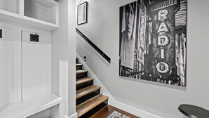 A staircase with wooden steps and a black railing, leading to a landing with a black and white patterned rug. - Two Luxury WeHo Homes w/ Rooftops + 6BR Near DT (Nashville)