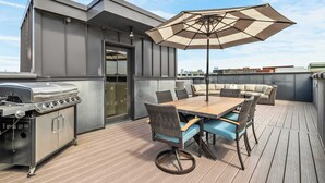 An outdoor patio with a dining table, chairs, a grill, and an umbrella. - Two Luxury WeHo Homes w/ Rooftops + 6BR Near DT (Nashville)