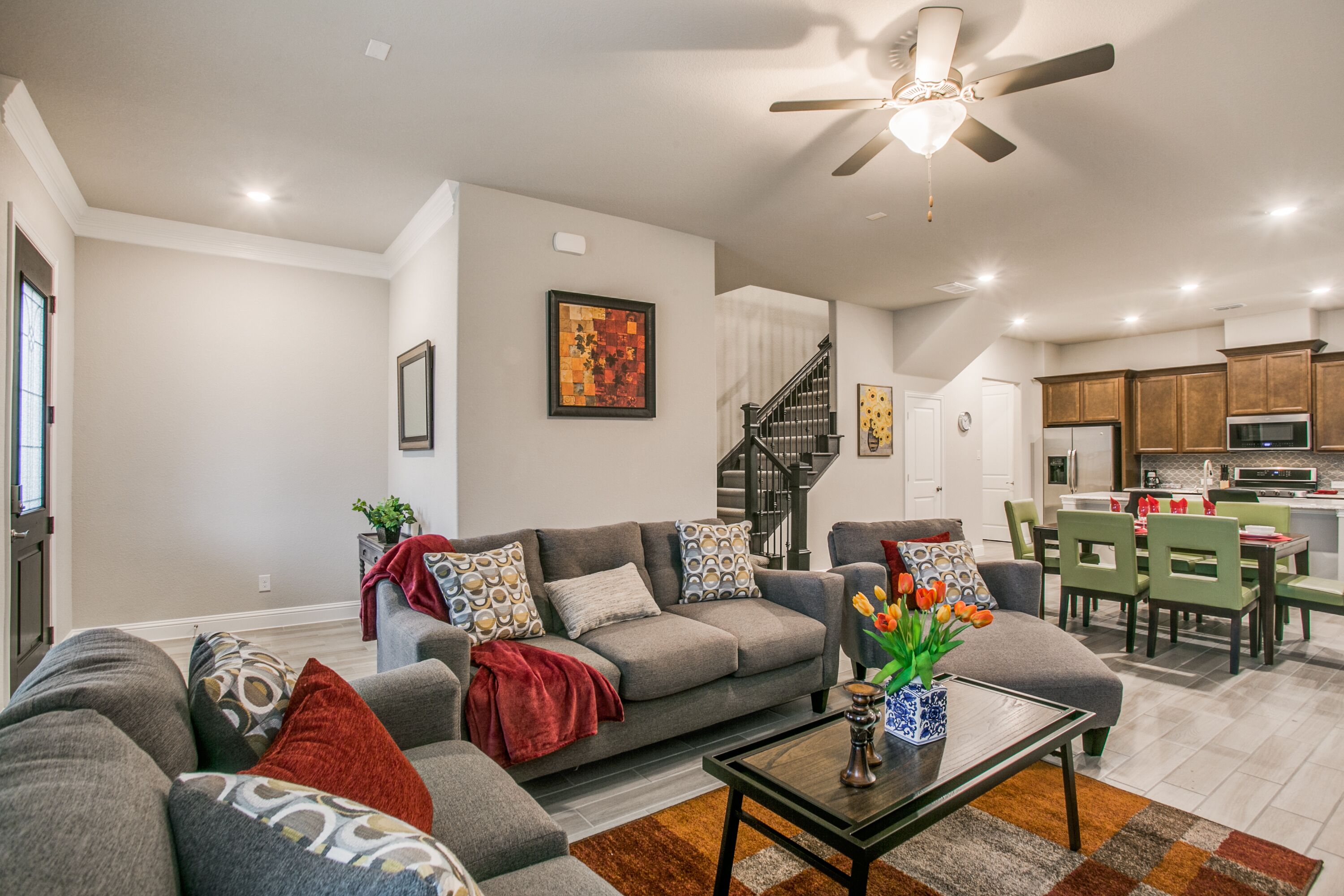 A modern living room with a grey sofa, a coffee table, and a staircase leading to the kitchen.