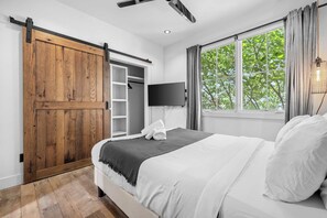 A bedroom with a large bed, a sliding door closet, a flat-screen TV, and a window with curtains. - Luxe WeHo Gem | Rooftop Views • DT • Nightlife (Nashville)