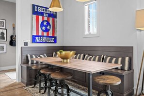 A dining area with a bench, stools, a table, and a wall decoration. - Luxe WeHo Gem | Rooftop Views • DT • Nightlife (Nashville)