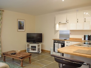 A modern kitchen with a flat-screen TV, wooden dining table, and white cabinets. - 1 bedroom accommodation in Edwyn Ralph, near Bromyard (Edwyn Ralph, near Bromyard)