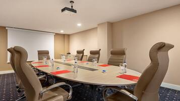 A conference room with a round table, six chairs, a projector, and a whiteboard.