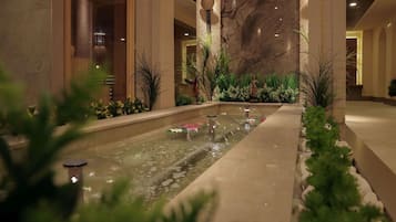 Una fuente interior tranquila rodeada de vegetación y paredes de mármol.