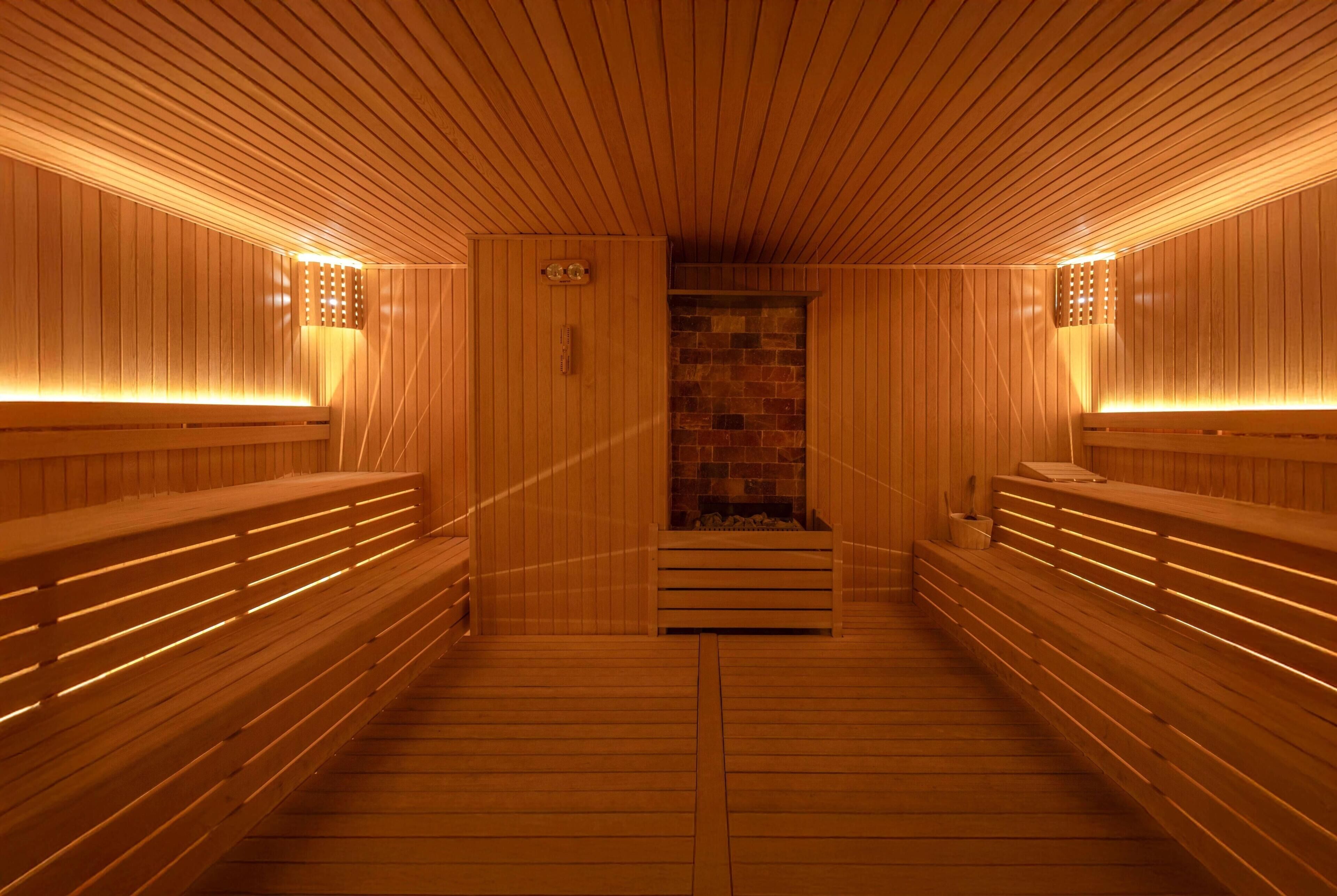 Uma sauna com bancos de madeira e uma parede de pedra ao centro.