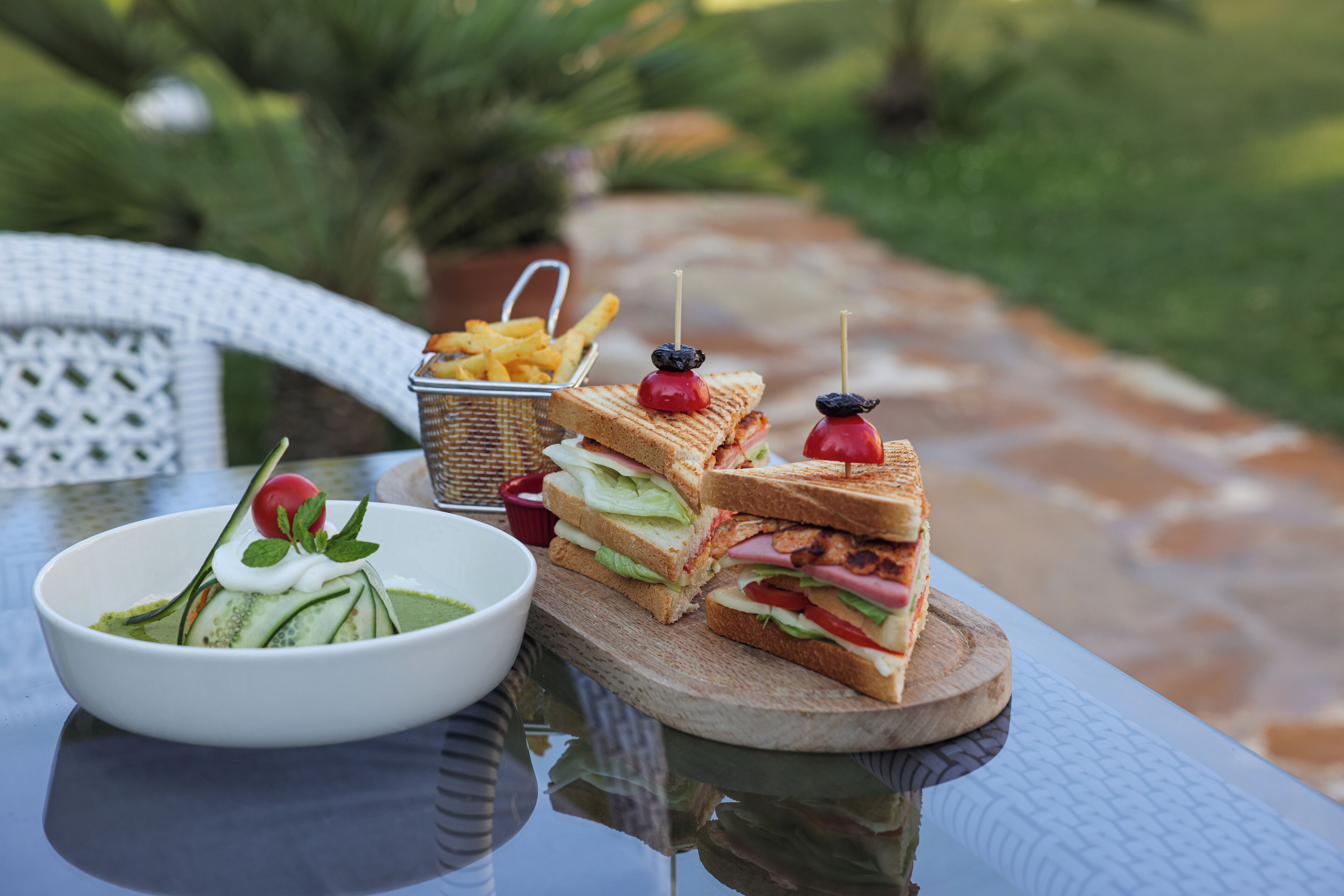 Una mesa con un sándwich, un plato de ensalada y una cesta de papas fritas.