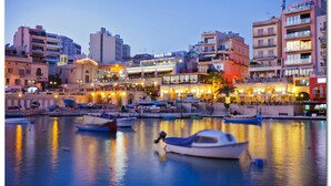 Una zona ribereña con barcos amarrados, edificios con tiendas y un llamativo letrero de Dolce Vita.