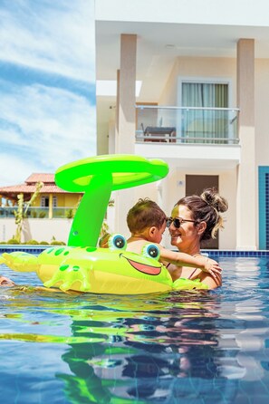 A swimming pool with a child and an adult. - Orquídeas Praia Hotel (Porto Seguro)