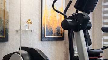 A gym with exercise equipment, including a treadmill and elliptical machine, and artwork on the walls.