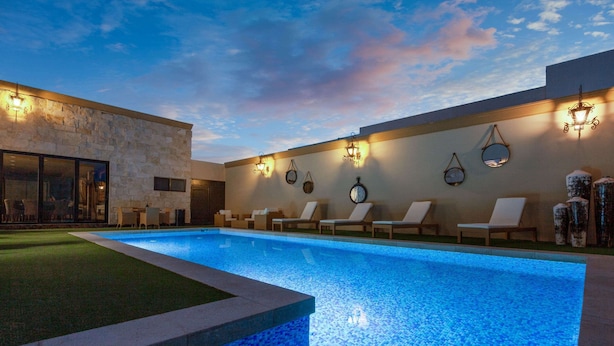 Piscina com espreguiçadeiras e iluminação embutida na parede.