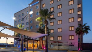 Um hotel Wyndham com vários andares, entrada coberta e palmeiras.