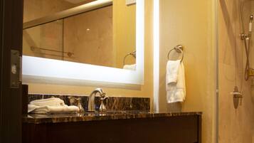 Un baño con un espejo grande, un lavamanos y una ducha.