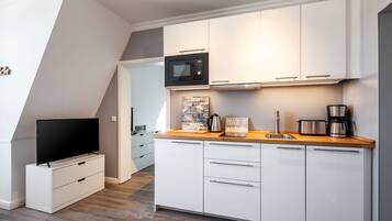 Eine moderne Küche mit weißen Schränken, einer Mikrowelle, einer Kaffeemaschine und einem Toaster.