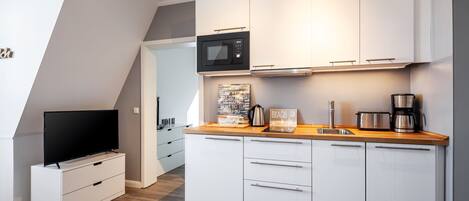 A modern kitchen with white cabinets, a microwave, a coffee maker, and a toaster.