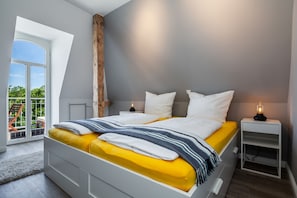 Un dormitorio moderno con cama, mesitas de noche y vistas al exterior.