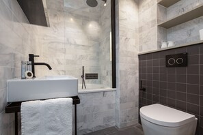 Een bad/douchecombinatie, een haardroger, handdoeken