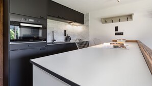 A modern kitchen with dark cabinetry, a built-in oven, and a white countertop. - Résidence Grands Montets 211 Walk to Ski Lift | Argentière Chamonix, Argentière (Chamonix), France (Argentière (Chamonix))
