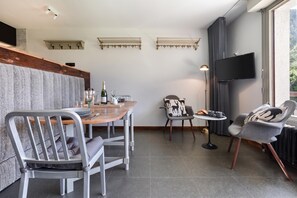 Un salon moderne comprenant un coin repas, un téléviseur fixé au mur et une fenêtre avec des rideaux.