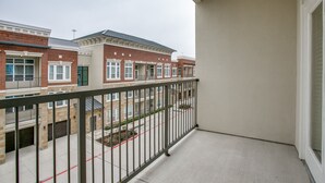 Ein Balkon mit Metallgeländer, der auf eine Reihe von Reihenhäusern blickt.