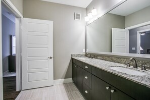 A bathroom with a double sink vanity, dark cabinets, and a large mirror.