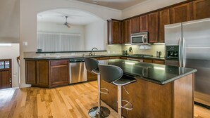 Een moderne keuken met houten kastjes, roestvrijstalen apparatuur en een centraal eiland met barstoelen.