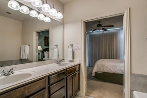 A bathroom with two sinks, a large mirror, and a ceiling fan. - Stylish 3 bedroom Town Home at shops at (Plano)