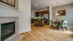 Een moderne keuken met houten kastjes, een centraal eiland met barstoelen, een eethoek met tafel en stoelen, en een plafondventilator.