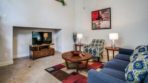 A living room with a TV, sofa, chairs, and a fireplace. - Beautifully furnished TownHome at shops (Plano)
