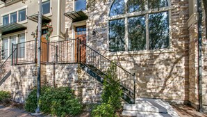 A stone building with a metal staircase leading to a door, surrounded by greenery. - Beautifully furnished TownHome at shops (Plano)