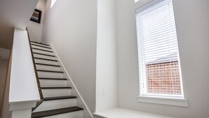 A staircase with white walls and a window with blinds. - Upscale 2 bedroom Dallas TownHome (Dallas)
