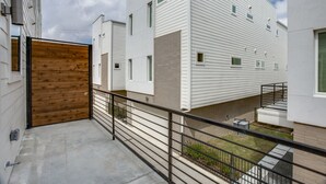 A modern apartment building with a wooden door, a balcony with a metal railing, and a small garden area. - Upscale 2 bedroom Dallas TownHome (Dallas)