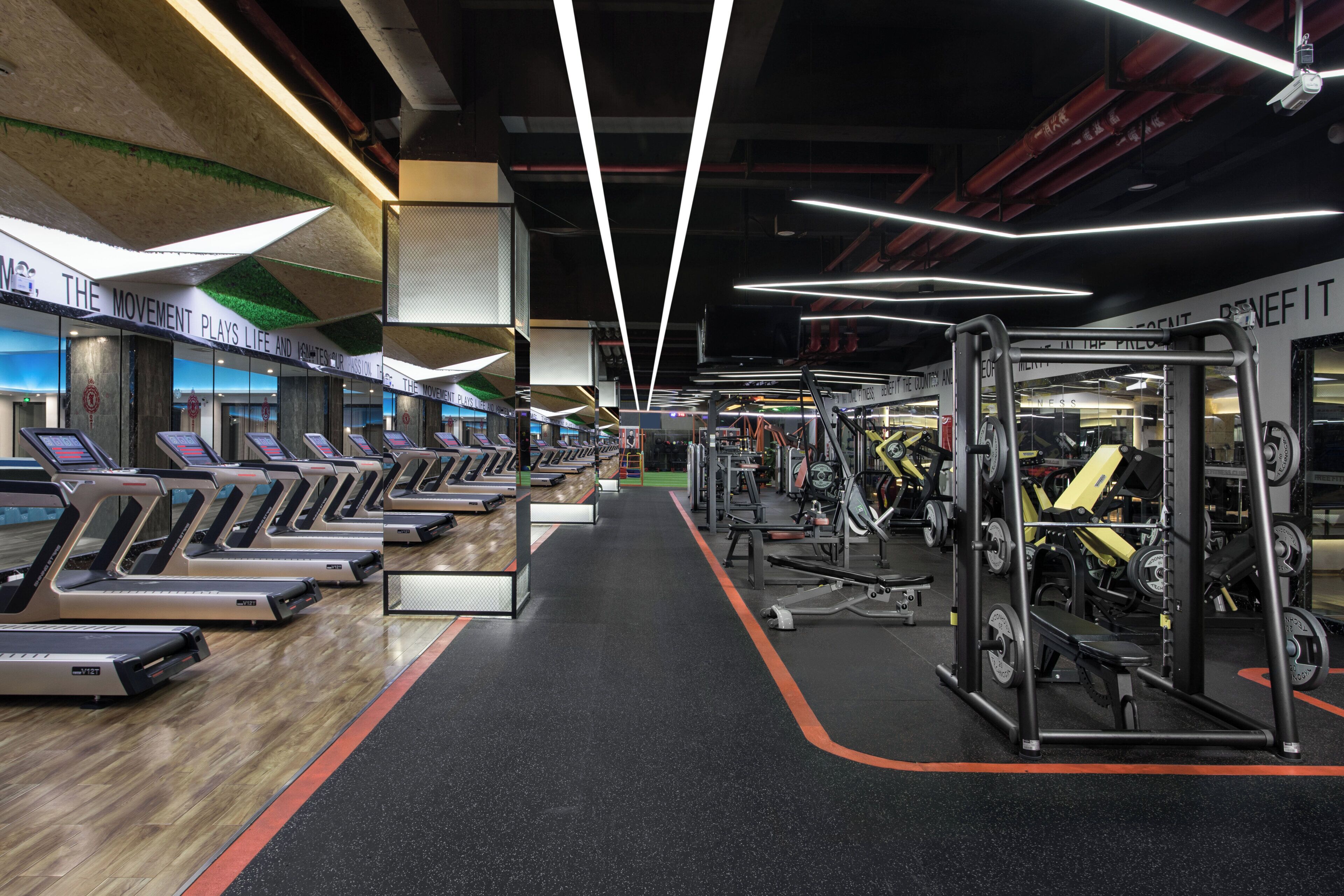 A gym with treadmills, weight machines, and a mirrored wall.