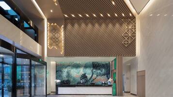 A modern reception area with a geometric patterned wall, a reception desk, and a glass entrance.