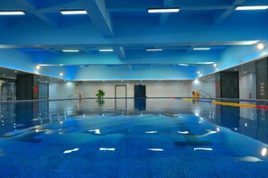 A large indoor swimming pool with clear lanes, a central plant, and a modern ceiling design. - Holiday Inn Guiyang City Center by IHG (Guiyang)