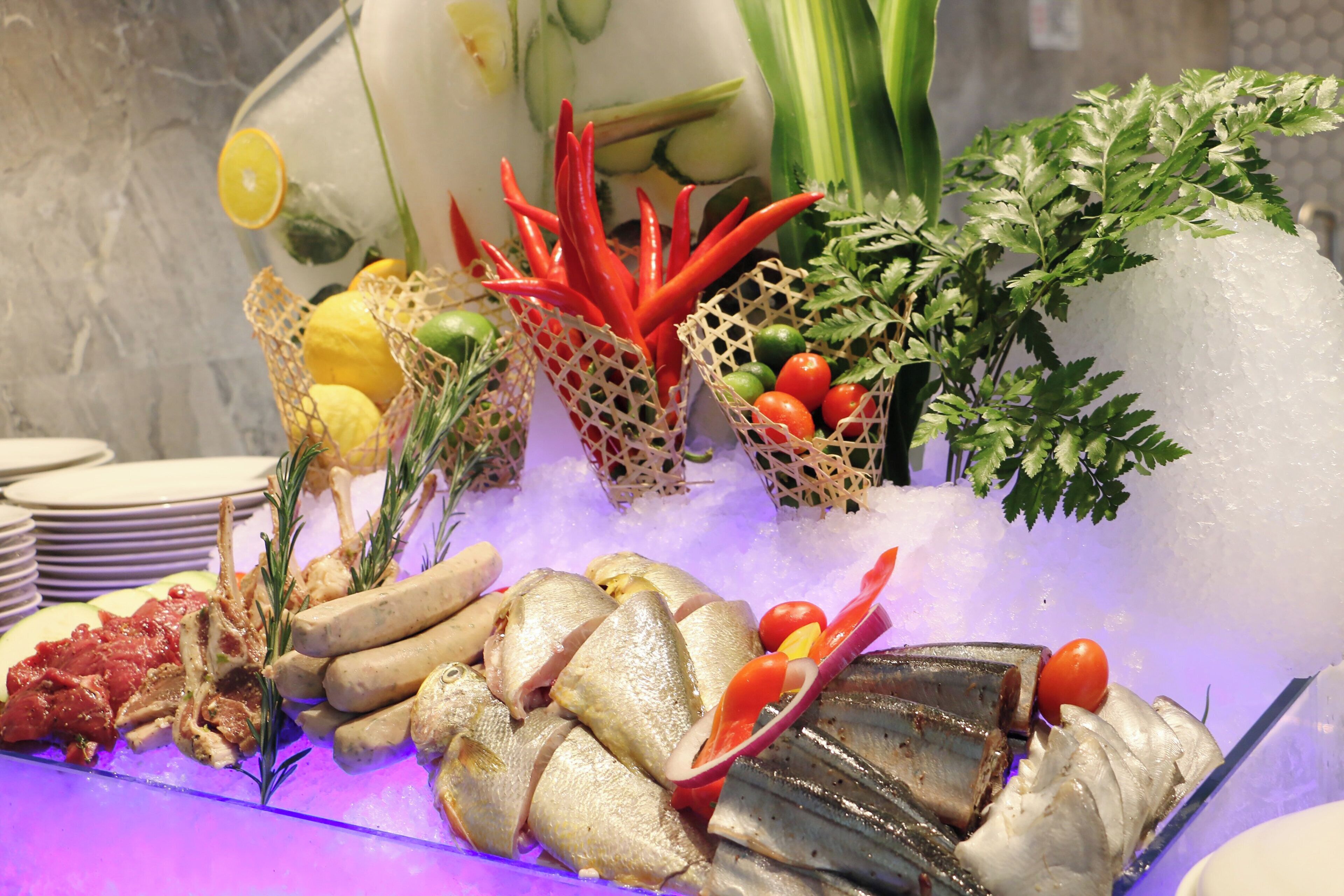 A seafood display with various fish, vegetables, and herbs on ice.