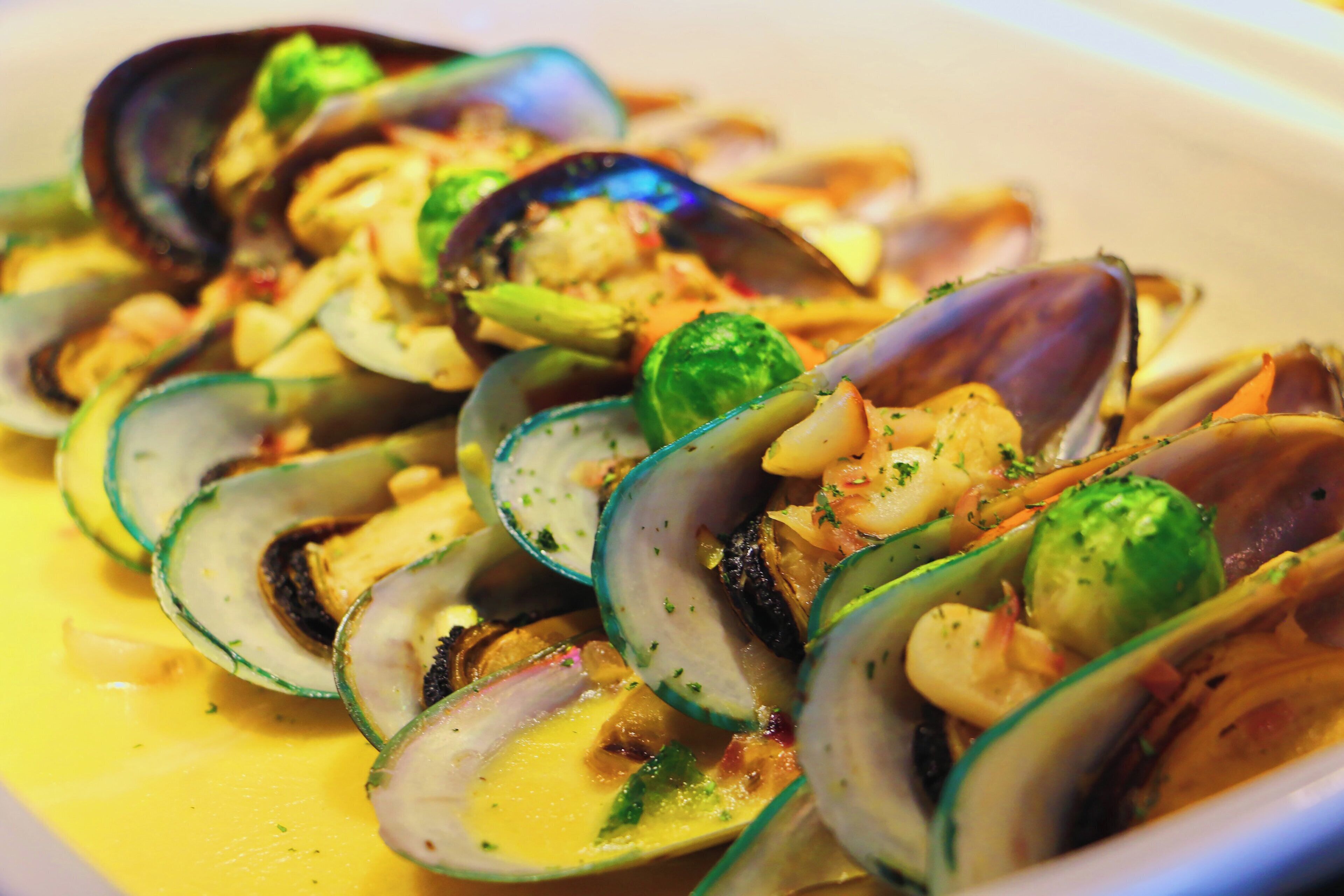 Un plat de moules accompagnées de légumes et nappées d’une sauce crémeuse.