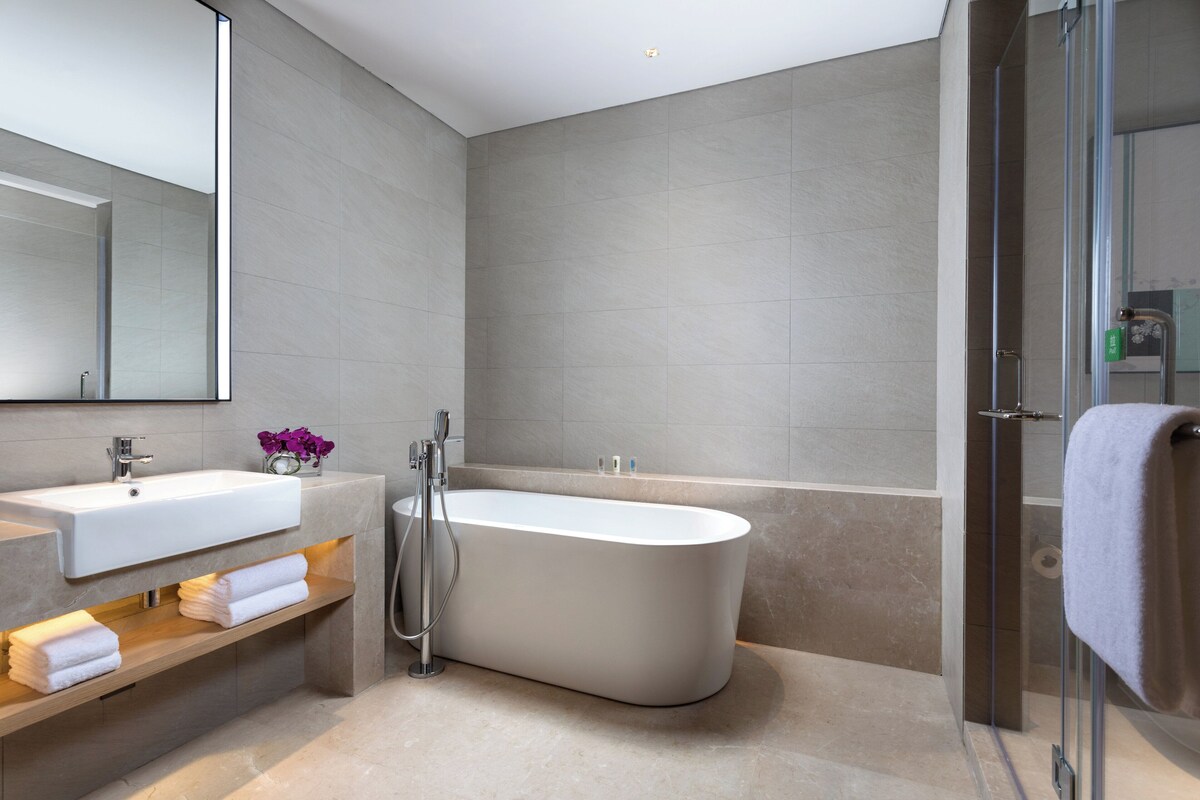 A modern bathroom with a freestanding bathtub, a vanity with a mirror, and a glass shower enclosure.