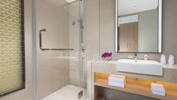 A modern bathroom with a glass shower enclosure, a white sink, and a mirror above it.