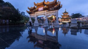 A traditional Chinese gate with intricate designs and a reflection on the wet ground. - Holiday Inn Guiyang City Center by IHG (Guiyang)