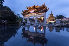A traditional Chinese gate with intricate designs and a reflection on the wet ground.