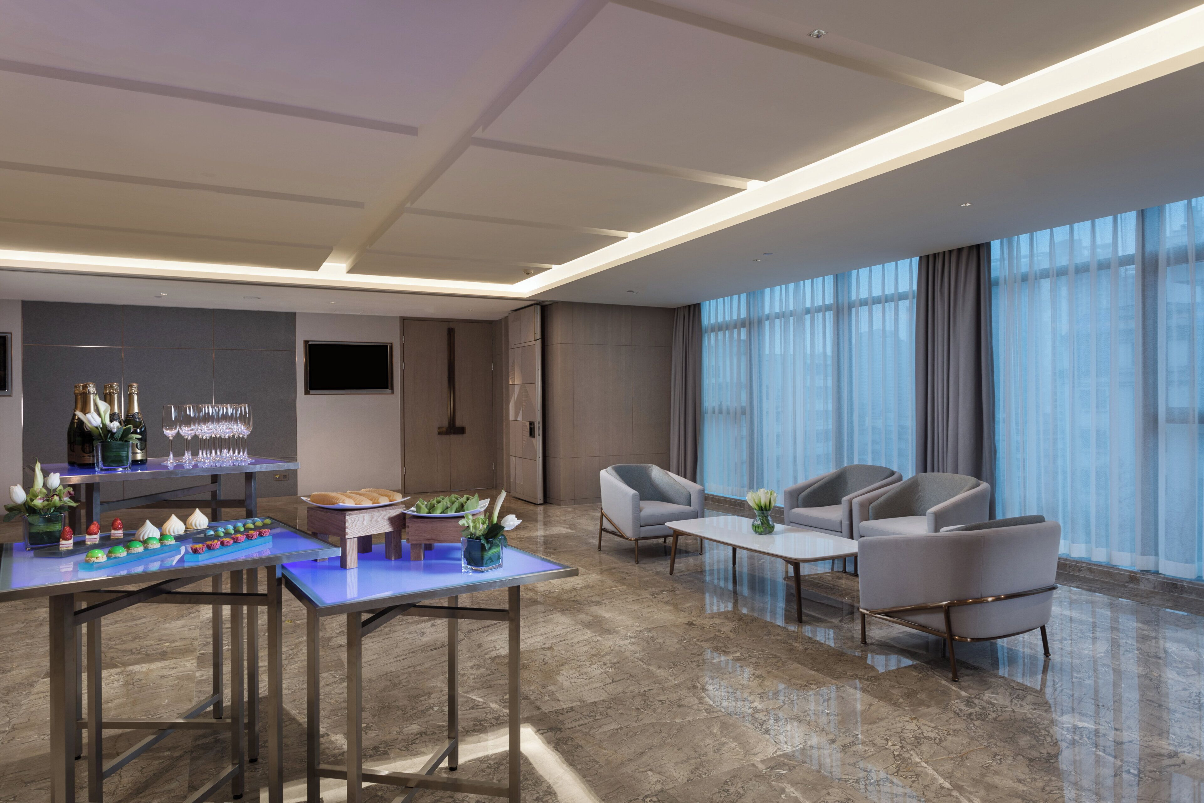 Un lobby moderno de hotel con zona de bar, asientos y un amplio ventanal.